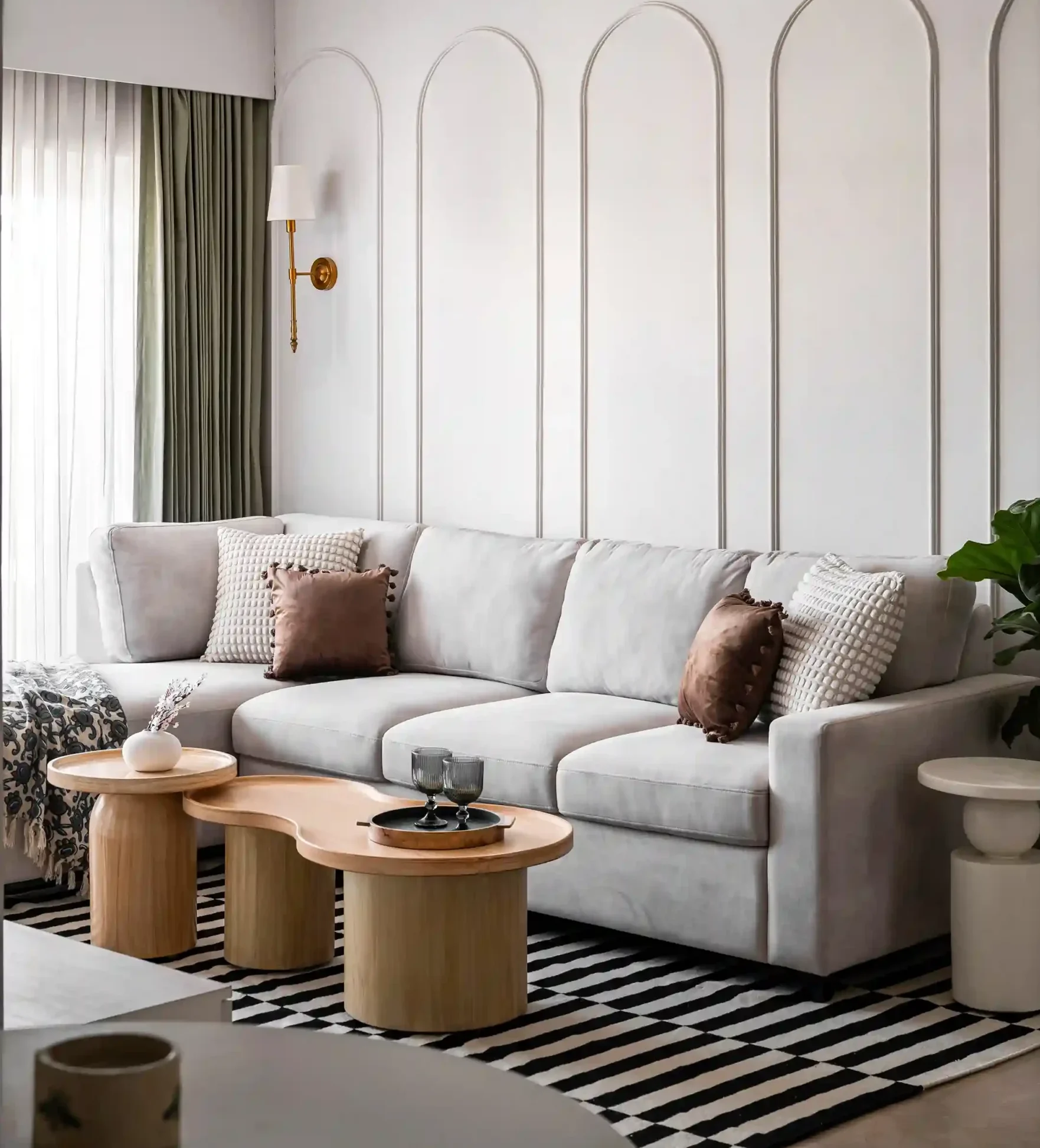 Modern living room featuring a gray sofa with textured pillows, stylish side tables, and a striped rug, against an elegant wall design.